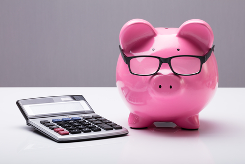 Pink piggy bank with glasses near a mortgage calculator